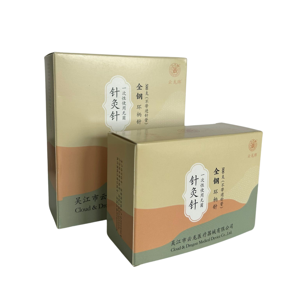 Dos cajas de agujas de acupuntura Cloud & Dragon con diseño beige, verde y naranja. Las cajas están posicionadas una frente a la otra mostrando sus etiquetas impresas en chino e inglés. Fondo transparente.