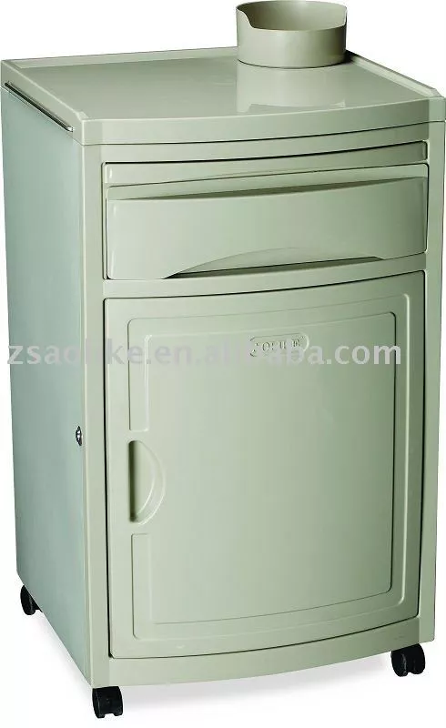 Mesa de noche clínica color beige con estructura robusta de acero. Incluye un cajón superior, un compartimento inferior con puerta y un soporte para botella de agua en la parte superior. La base tiene cuatro ruedas giratorias negras para facilitar la movilidad.